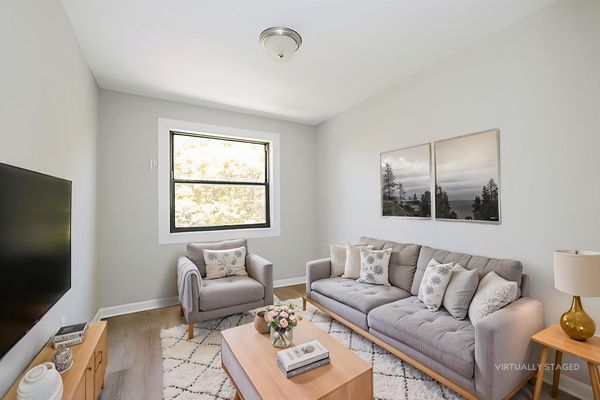 Living room virtually staged with sofa, armchair, and television