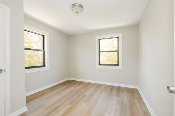 Primary bedroom shown vacant with hardwood floors and large window